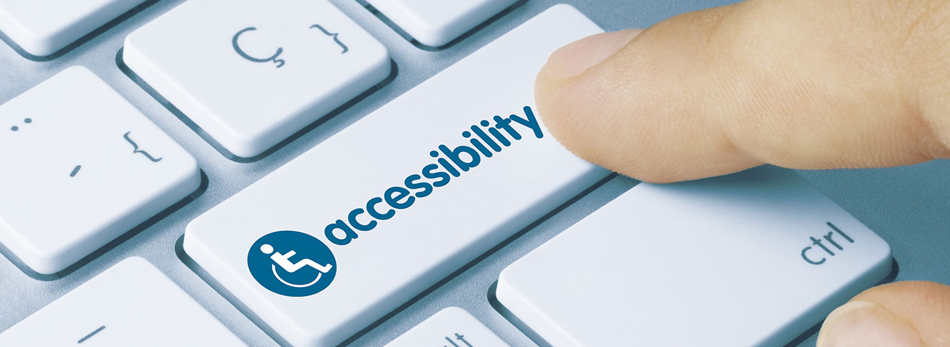 Close up shot of a finger clicking on a button on a keyboard. The button says accessibility next to an icon of a person in a wheelchair.