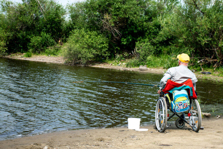 Man in a wheelchair fishing at a lake.