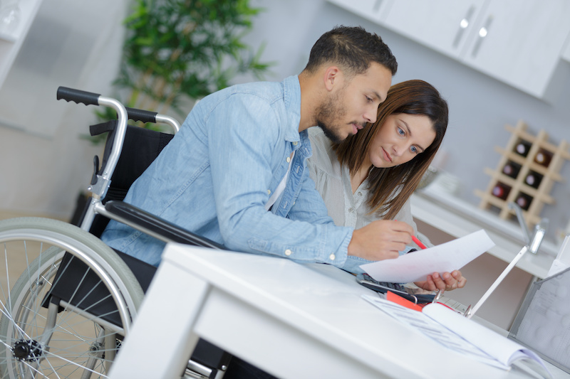 couple at home reading document, man in wheelchair