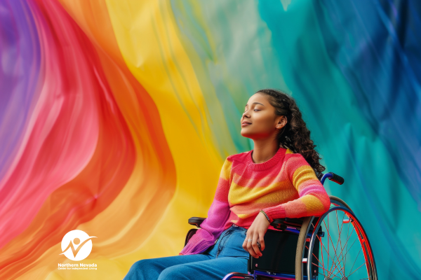 Young woman wearing a rainbow-colored shirt, sitting in a wheelchair with rainbow colors behind her.