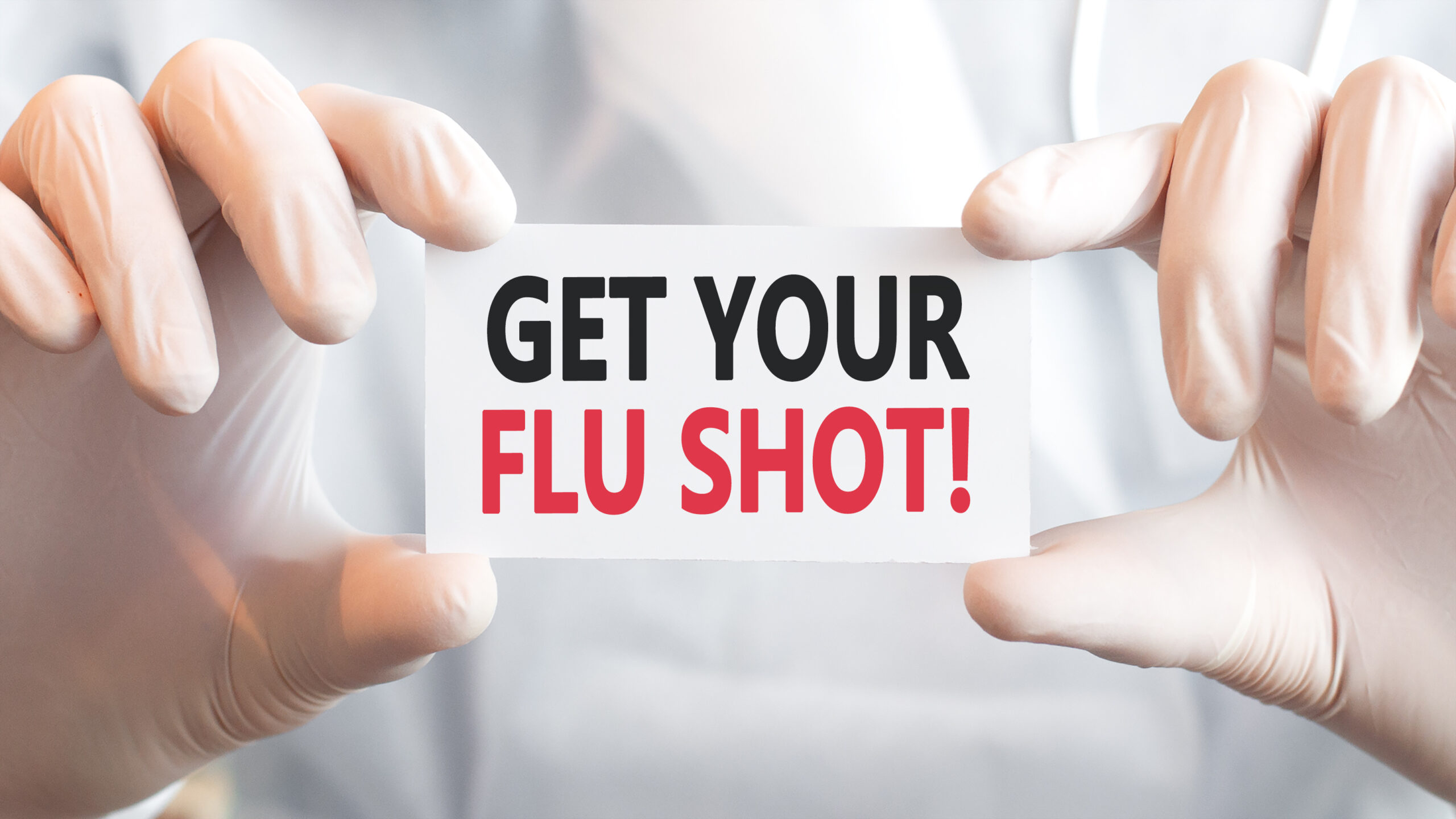 Doctor holding a card with text get your flu shot in both hands.