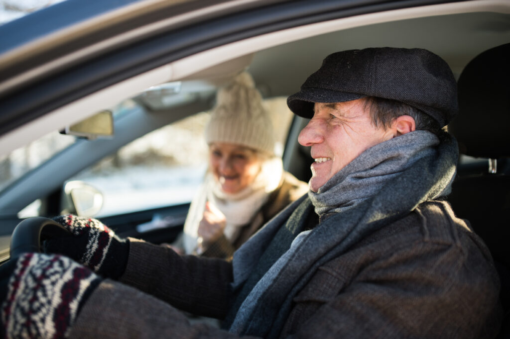 Older couple driving in the snow.